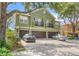 Exterior shot showcasing a three-car garage with a landscaped front yard and natural shade from mature trees at 2430 Little Gem Loop, Sanford, FL 32773