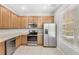 A functional kitchen featuring stainless steel appliances, wood cabinets, and tile flooring at 2430 Little Gem Loop, Sanford, FL 32773