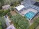 Aerial view of a home's backyard featuring a screened-in pool, brick patio, and a shed surrounded by mature trees at 2550 Meadowview Ln, Deland, FL 32720