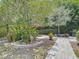 The backyard has many landscaped areas including a brick-paved walkway, a patio with outdoor dining, and a grill at 2550 Meadowview Ln, Deland, FL 32720