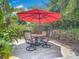 A backyard patio with a round patio table, 4 chairs, and a red umbrella for shade at 2550 Meadowview Ln, Deland, FL 32720