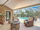 This covered lanai features stone accents, wicker furniture, a fire pit, and views of the pool and back yard at 2550 Meadowview Ln, Deland, FL 32720