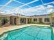 Aerial view of the pool, pool deck, screened enclosure, lanai, lush landscaping, and the back of the house at 2550 Meadowview Ln, Deland, FL 32720