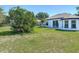 Large backyard showcasing a well-maintained lawn, complemented by a white house with a sliding glass door at 2620 Abbey Ave, Orlando, FL 32833