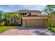 Elegant two-story home with a two car garage, lush landscaping, and a paver driveway at 3041 Boating Blvd, Kissimmee, FL 34746