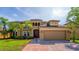 Elegant two-story home featuring a lush lawn, landscaping, paver driveway, and porte-cochere at 3041 Boating Blvd, Kissimmee, FL 34746