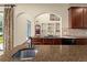 Granite kitchen island with a sink, wood cabinetry, and an archway with a view of the house at 3041 Boating Blvd, Kissimmee, FL 34746
