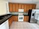 Practical kitchen with wood cabinets, granite counters, and stainless steel appliances on tile flooring at 3549 Wilshire Way Rd # 56, Orlando, FL 32829