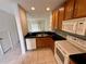 Well-lit kitchen with wood cabinets, black countertops, and modern appliances viewed from an open layout at 3549 Wilshire Way Rd # 56, Orlando, FL 32829