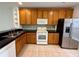 Functional kitchen with wooden cabinets, stainless steel appliances, and black countertops on tile flooring at 3549 Wilshire Way Rd # 56, Orlando, FL 32829
