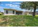 Lush backyard featuring an enclosed patio, healthy green lawn, and a mature shade tree at 5560 Squires Dr, Leesburg, FL 34748