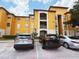Attractive yellow apartment building with three parked cars and manicured landscaping at 6169 Metrowest Blvd # 308, Orlando, FL 32835