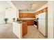 Kitchen with wooden cabinetry and white appliances open to a large living area at 6169 Metrowest Blvd # 308, Orlando, FL 32835