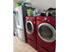 Modern laundry room featuring a red washer and dryer set, along with a stainless steel refrigerator at 6800 Se 12Th Pl, Ocala, FL 34472