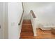 Hardwood steps with a dark trim going up a brightly lit stairwell at 6941 Piazza St, Orlando, FL 32819