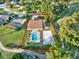 Aerial view of the property, featuring the house, pool, sand volleyball court, and verdant landscaping at 6969 Edgeworth Dr, Orlando, FL 32819