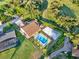 Aerial view shows house with tile roof, a pool and volleyball court on a large property surrounded by green foliage at 6969 Edgeworth Dr, Orlando, FL 32819