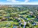 Scenic aerial view of a community featuring tree-lined streets, green spaces, and a lake in the distance with property pin at 6969 Edgeworth Dr, Orlando, FL 32819