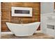 Luxurious bathroom showcasing a freestanding tub with wood accent wall and a modern fireplace at 6969 Edgeworth Dr, Orlando, FL 32819