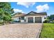 Elegant home with a clay tile roof, brick driveway, lush landscaping, and a two-car garage at 6969 Edgeworth Dr, Orlando, FL 32819