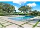 Backyard pool and sand volleyball court featuring a well-manicured lawn, greenery, and sunny skies at 6969 Edgeworth Dr, Orlando, FL 32819