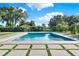 Beautiful backyard pool with green grass accents, lush greenery, and blue skies at 6969 Edgeworth Dr, Orlando, FL 32819