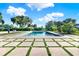 A sparkling pool features a unique concrete tile surround in a yard with trees and manicured shrubs, ready for backyard fun at 6969 Edgeworth Dr, Orlando, FL 32819