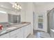 The luxury bathroom features double sinks, granite counters and a large glass shower at 7263 Oakmoss Loop, Davenport, FL 33837