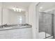 Bathroom with double sinks, granite counters, white cabinets, and glass enclosed shower at 7263 Oakmoss Loop, Davenport, FL 33837
