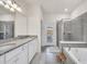 The luxury bathroom features double sinks, granite counters and a large glass shower at 7263 Oakmoss Loop, Davenport, FL 33837
