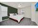 Bedroom with green accent wall, carpeted floor, queen bed, ceiling fan, and natural light at 7263 Oakmoss Loop, Davenport, FL 33837