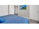 Bedroom with blue queen bed, carpeted floors, white trim, and a television mounted to the wall at 7263 Oakmoss Loop, Davenport, FL 33837