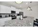 Close-up of a modern kitchen with stainless steel appliances, white cabinetry, and granite countertops at 7263 Oakmoss Loop, Davenport, FL 33837