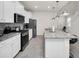 Well-lit kitchen featuring white cabinets, stainless steel appliances, and a granite island at 7263 Oakmoss Loop, Davenport, FL 33837