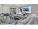 Sunlit living area features a gray sectional and a view of the backyard pool at 7263 Oakmoss Loop, Davenport, FL 33837