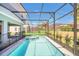 Sparkling pool in a screened enclosure, surrounded by lush landscaping, offering privacy and relaxation at 7263 Oakmoss Loop, Davenport, FL 33837