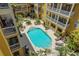 Aerial view of a community swimming pool with lounge chairs and well-maintained landscaping between yellow buildings at 860 N Orange Ave # 448, Orlando, FL 32801
