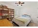 Bright bedroom with large bookshelf and a comfortable bed, illuminated by a ceiling fan at 9356 St Therese St, Groveland, FL 34736