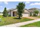 Traditional-style home with a manicured lawn, two-car garage, and neutral-toned exterior at 9356 St Therese St, Groveland, FL 34736