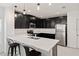 Modern kitchen with black cabinetry, white quartz countertops, stainless steel appliances, and a breakfast bar at 9356 St Therese St, Groveland, FL 34736