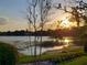 Scenic lake view with a sunset, lush grass, and a dock on the water at 983 Bucksaw Pl, Longwood, FL 32750