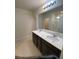 Bright bathroom featuring double sinks with dark cabinets and large mirror at 1575 Aspen Ave, Davenport, FL 33837