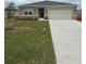 Charming single-story home with well-maintained lawn and a two car garage on a cloudy day at 1575 Aspen Ave, Davenport, FL 33837