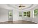 Bright bedroom featuring tray ceiling, ceiling fan, multiple windows for ample natural light, and wood flooring at 1601 Stargazer Ter, Sanford, FL 32771