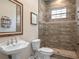 Bathroom featuring a white toilet, sink, mirror, tiled shower stall, and sign at 20199 Sweetwood Ln, Clermont, FL 34715