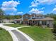 Stunning exterior elevation with stone accents, a long driveway, and lush landscaping at 20199 Sweetwood Ln, Clermont, FL 34715