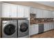Well-equipped laundry room with modern washer, dryer, sleek countertops, and ample cabinet space at 20199 Sweetwood Ln, Clermont, FL 34715
