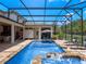 Luxurious screened-in pool featuring a waterfall, patio seating, an outdoor shower, and lush landscaping at 20199 Sweetwood Ln, Clermont, FL 34715