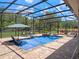 Beautifully landscaped pool with a screened enclosure, patio seating, and a tranquil waterfall feature at 20199 Sweetwood Ln, Clermont, FL 34715