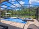 Inviting screened-in pool area with a spa, waterfall feature, and comfortable seating at 20199 Sweetwood Ln, Clermont, FL 34715